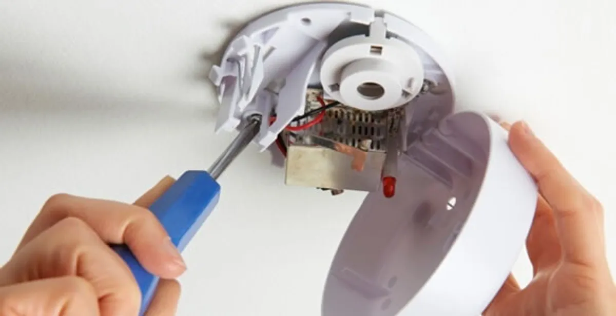 Certified technician wiring smoke detector during installation in West Palm Beach, FL